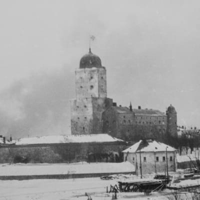 Viborg slott med finska flaggan höjd medan Viborg stad brinner i bakgrunden under slutskedet av vinterkriget. SA-kuva.