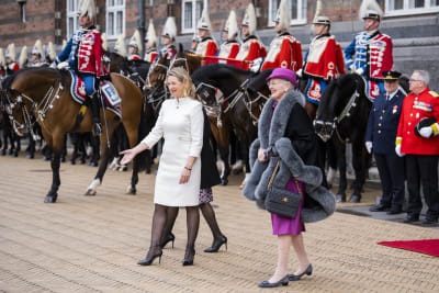 Köpenhamns borgmästare Sophie Hæstorp Andersen och drottning Margrethe II ler vid Köpenhamns rådhus. Bakom dem syns en rad hästar med ryttare i paraduniform.