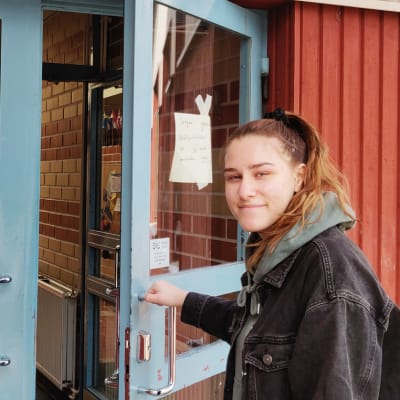 En ung kvinna öppnar en dörr. Till vänster synns en plansch där det framkommer att det här är en vallokal i Boxby skola.