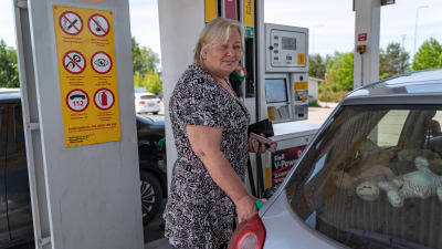 Sommarklädd kvinna tankar sin personbild på en bensinstation