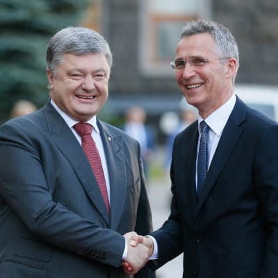 Kuvassa Ukrainan presidentti Petro Poroshenko vasemmalla ja Jens Stoltenberg oikealla. He kättelevät ja hymyilevät. 