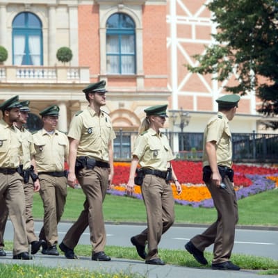 Seitsemän poliisia marssii Bayreuthin oopperajuhla-alueella. 