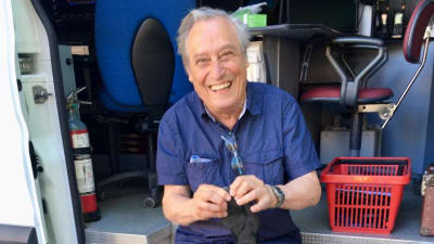 Professori Ralf Gothoni istuu nauraen pakettiauton takapuskurilla ja pitelee käsissään rikkinäistä kenkää.