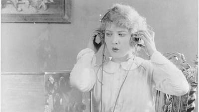 Kvinna lyssnar på radio med hörlurar.