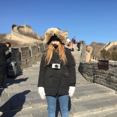 Marian Krok seisoo Kiinan muurilla talvitakki päällä.