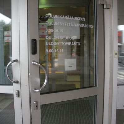 Oulun käräjäoikeuden ja syyttäjänviraston ulko-ovi hivenen avoinna.
