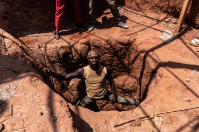 En man klättrar ner i ett gruvhål.
