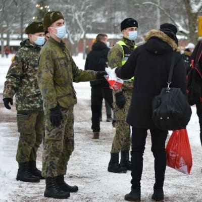 Många personer köar utanför porten till Nylands brigad. Det är vinter och alla bär munskydd.