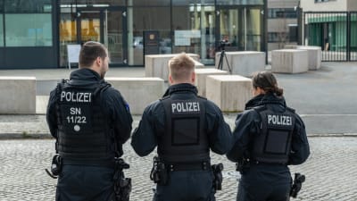 Tre tyska poliser i uniform står med ryggen emot. 
