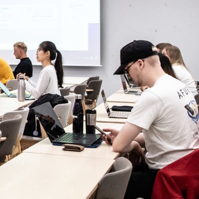 Aalto-yliopiston kesäkurssin opiskelijoita luokkahuoneessa ja etäyhteydellä mukana muita opiskelijoita ympäriä Suomean ja muuta maailmaa.