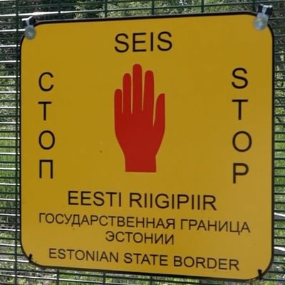 En skylt som säger stop här går Estlands gräns mot Ryssland på ett gränsstaket