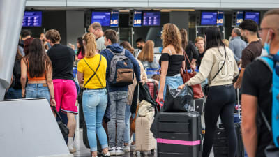 Personer står i kö på en flygplats.