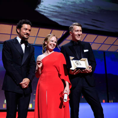 Orlando Bloom, Alma Pöysti och Jussi Vatanen ler mot kameror.