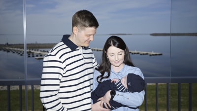 Niklas Hakalax ja hänen vaimo pitelevät heidän vauvaa sylissä parvekkeella.