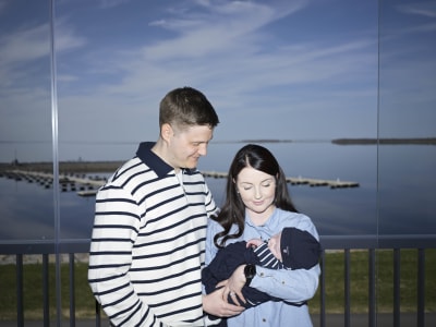 Niklas Hakalax står invid sin fru som håller deras bebis i famnen.