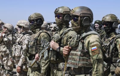 Soldater i utrustning står på rad. En av dem har en rysk flagga på armen.