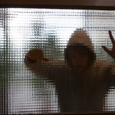 Anonym ung beter sig våldsamt bakom en glasvägg.