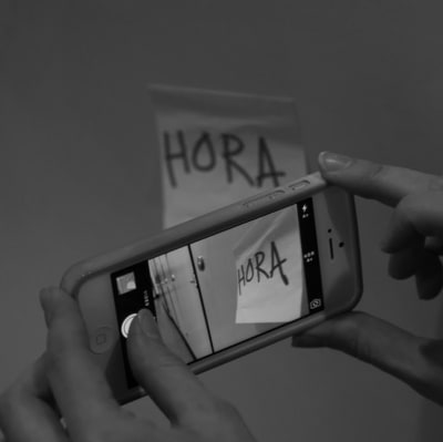 En mobiltelefon fotar en lapp med texten "hora".
