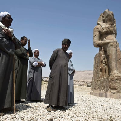 Kaapuihin pukeutuneita miehiä seisomassa vastapaljastetun farao Amenhotep III:ta esittävän patsaan vierellä Luxorissa, Egyptissä 23. maaliskuuta 2014.