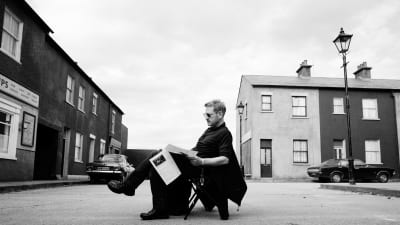 Kenneth Branagh istuu ohjaajan tuolilla käsikirjoitusta lukien aukion keskellä Belfastissa.