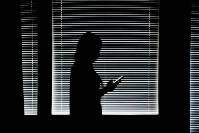 Kvinna med telefon i mörkt rum.