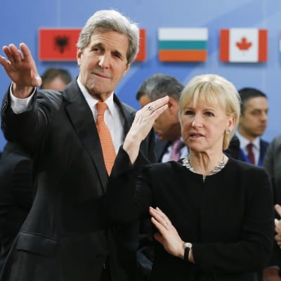 John Kerry ja Margot Wallström katsovat ohi kameran Kerryn käden osoittamaan suuntaan.