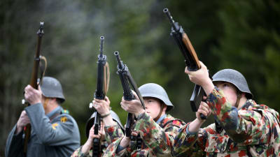Fyra schweiziska soldater siktar med gevär på en militärövning.