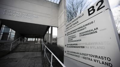 En skylt som det står "Esbo rättshus" på. I bakgrunden syns en modern byggnad.