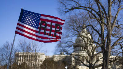 USA:s flagga med texten RIP. I bakgrunden syns Kapitoliums kupol.