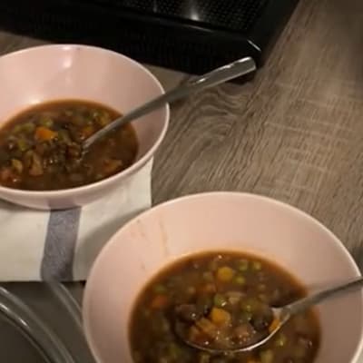 kaksi lautast keittoa ja käsi pitelee lusikkaa