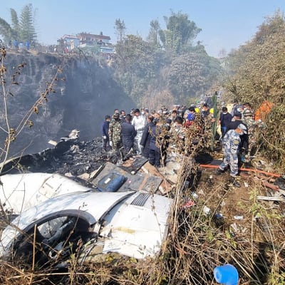 Räddningsarbetare vid delar av ett kraschat flygplan i Nepal.