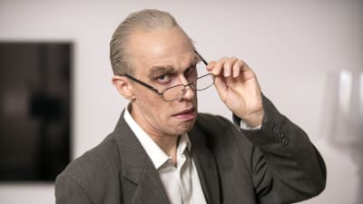 Christoffer Strandberg utklädd till Jörn Donner. Han är sminkad för att se gammal ut samt har stora ögonbryn. Han har också på sig en säckig kavaj och glasögon. 
