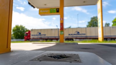 En stängd bensinstation i förgrunden, i bakgrunden en långtradare som åker förbi.