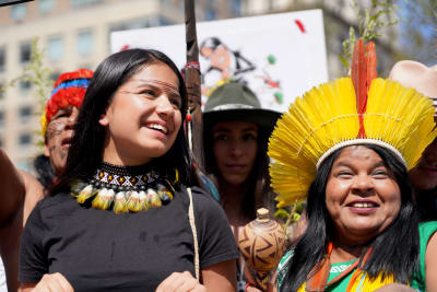 två kvinnor från ursprungsbefolkningen i ecuador, en äldre och en yngre, står bredvid varandra i en demonstration. de har färgglatt halsband och huvudbonad på sig och den yngre kvinnan är målad i ansiktet
