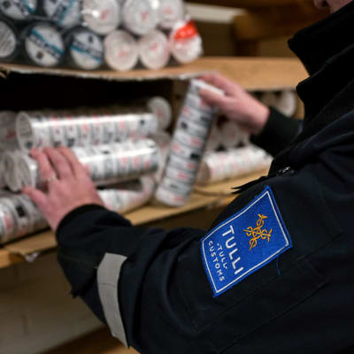Tullitarkastaja tutkii takavarikoituja nuuskapaketteja Tullin takavarikointivarastossa Torniossa 12. lokakuuta 2022.