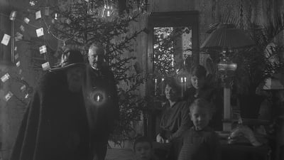 Julbocken på besök hos familj i vardagsrum med upplyst julgran