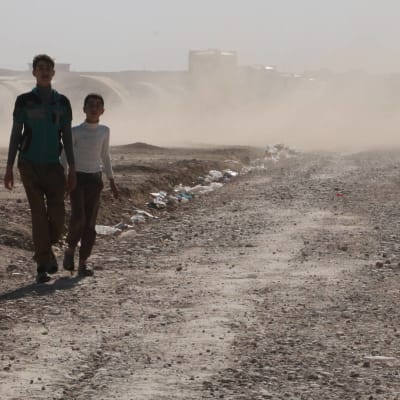 pojkar i dammet på flyktingläger utanför Mosul