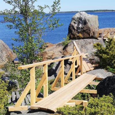 Kesäisessä saaressa epätasaisen maaston polkuja tasoittavat vastatehdyt puiset sillat.