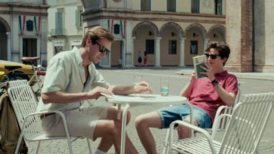 Oliver (Armie Hammer) och Elio (Timothée Chalamet) sitter vid en utomhusservering och pratar. 
