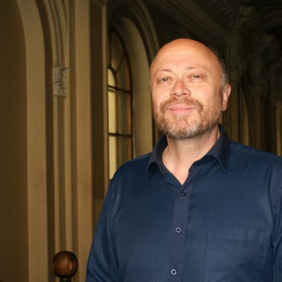 partasuinen mies hymyilee aavistuksen verran