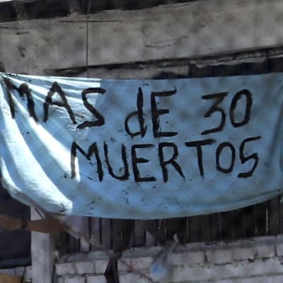 "Över 30 döda" står det på en banderoll utanför fängelset Modelo i Colombias huvudstad Bogota efter ett upplopp 22.3.2020
