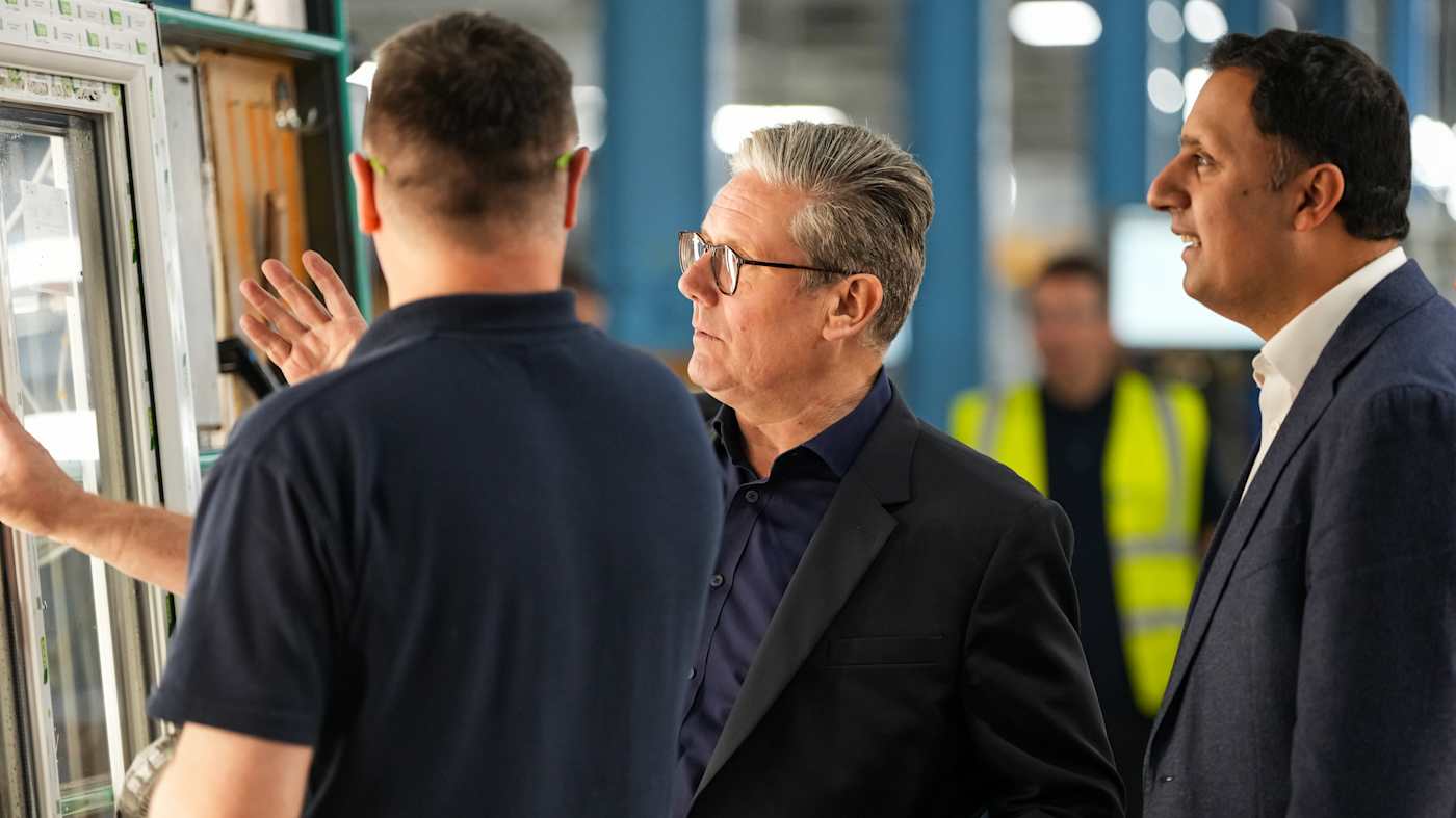 Three men look at goods in a British window shop.