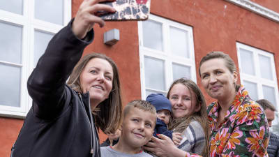 Tanskan pääministeri Mette Frederiksen (oik.) valokuvassa ihmisten kanssa kadulla.