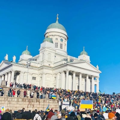 Photo of people protesting the attack on Ukraine at Helsinki's Senate Square on 26 February 2022, featuring the All Points North podcast logo.