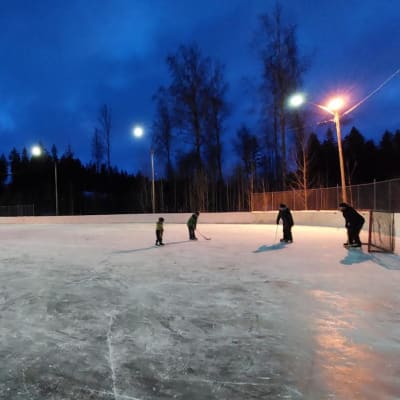 Barn skrinnar och spelar med klubbor på Isnäs sportplan.