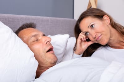 Kvinna tittar utamattat på sovande man som har öppen mun