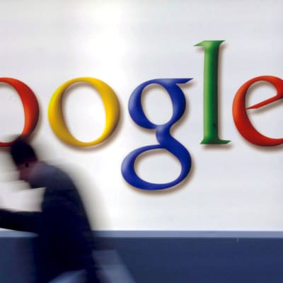 Mies kävelee ohi seinässä olevan Googlen logon.