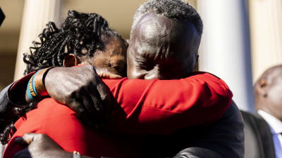 Den dödade joggaren Ahmaud Arberys far Marcus Arbery kramar om en kvinna efter att gärningsmännen fällts för mord. 
