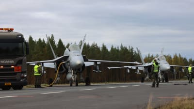 Två Hornet-jaktplan på en landsväg, det ena tankas via en militär tankbil som delvis syns i bild.