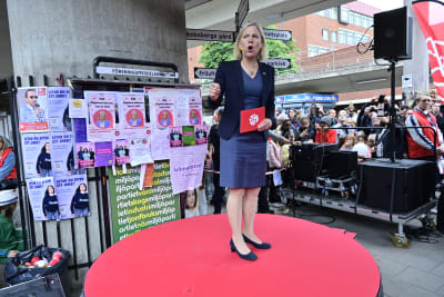 Magdalena Andersson står på ett rött podium och talar.